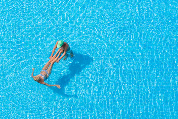 Couple relaxing swims in hotel pool.