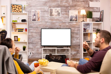 Couple looking at isolated TV screen in cozy living room