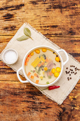 Transparent duck broth with dumplings and vegetables. Traditional bouillon, healthy food. Old wood background