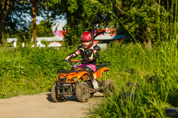 Little girl riding ATV quad bike in race track