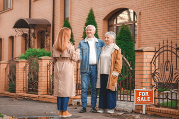 Fototapeta premium Female real estate agent with clients near building for sale