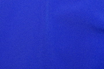 The texture of a knitted woolen fabric textile in classic blue trendy color. Abstract background for design with soft waves