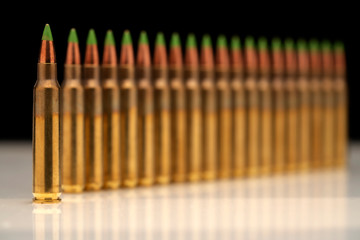 A group of 5.56 calibar, green tip bullets ordered into the line on black background