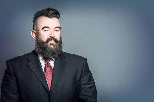 Adult bearded man in a suit with mohawk hairstyle on a blue background