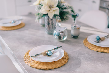 Cutlery and plates neatly placed on the kitchen table with Christmas decor