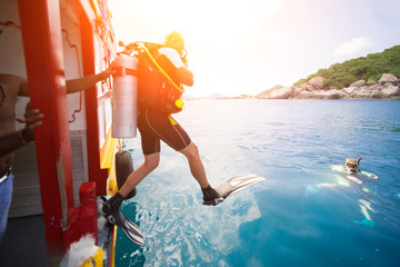 Male diver jumps into the sea from a yacht.