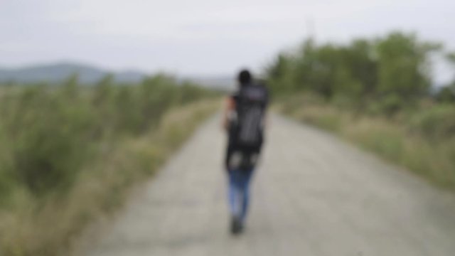 Blurred View of Girl Backpacker Walking on Countryside Road - Powered by Adobe