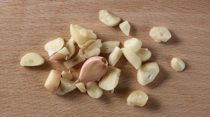 Garlic clove slices on wooden chopping board background and texture, top view