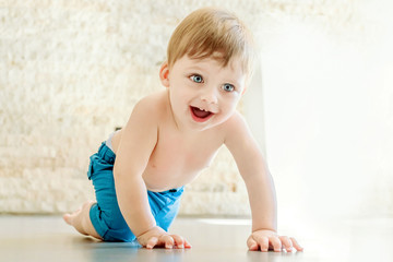 Smiling blue eyed blond babe crawling on the floor.