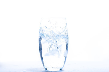 falling ice cube into a water glass making bubbles with a with background 