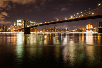 Brooklyn bridge in the night with reflections on the water