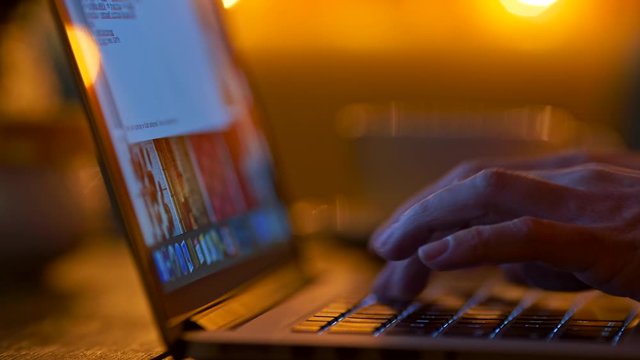 Female fingers typing on her laptop. Dark room at night. Sliding shot, UHD
