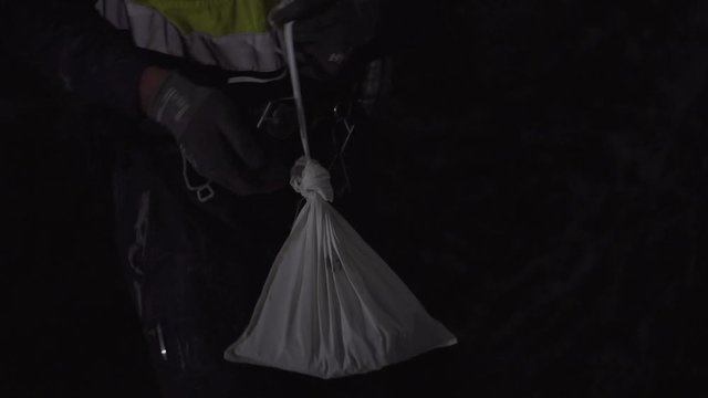 Close up of underground geologist tying calico sample bag in knot in slow motion