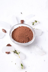 Cocoa powder on a white background next to ice