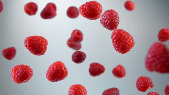 Ripe juicy raspberries bouncing up on white background in slow motion