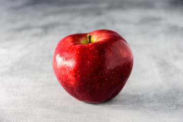 Big red apple on grey background