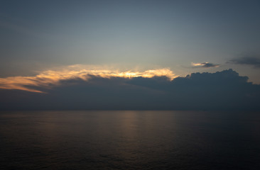 Sunset and dramatic set of clouds drifting over the tropical waters of the Caribbean Sea are lit by the last moments of daylight