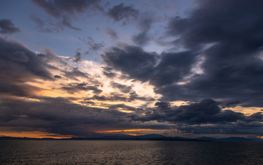 Sunset and dramatic set of clouds drifting over the tropical waters of the Caribbean Sea are lit by the last moments of daylight
