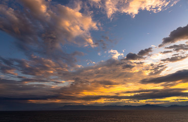 Sunset and dramatic set of clouds drifting over the tropical waters of the Caribbean Sea are lit by the last moments of daylight