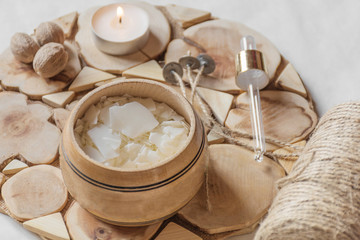 Tools for making candles of white soy wax flakes, essential oil, wicks on wooden background. Front view. Ecological lifestyle