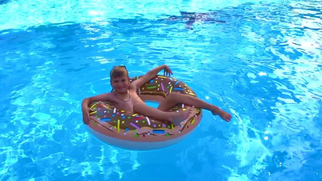 a boy swims on an inflatable donut in the pool. the concept of relaxation, summer holidays and travel