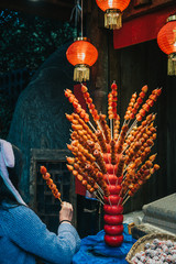 Woman buys and holds traditional Chinese dessert Tanghulu also called bingtanghulu, is a snack of candied fruit. Hawthorn Gourd caramelized sour on bamboo skewer sold on tourist pedestrian street.