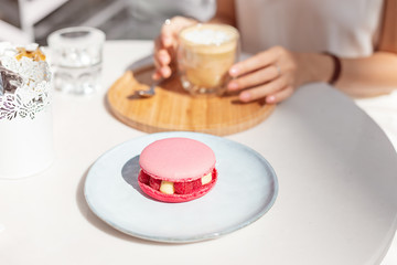 eating sweet pink macaroon with raspberries and drinking delicious pistachio coffee in a French cafe