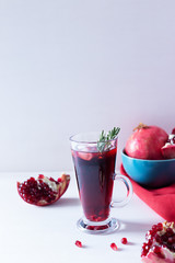 Pomegranate Christmas cocktail with champagne, soda and rosemary on a white table. Xmas drink.