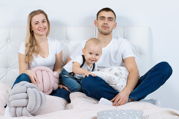 Mom, dad and little son are playing at home. Young family with a child.