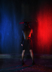 brunette in the rain in a black cloak and with an umbrella