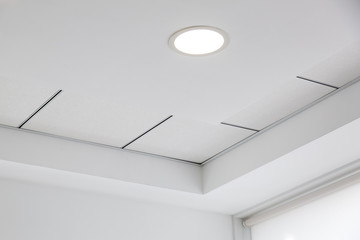 multi-level ceiling with three-dimensional protrusions and a suspended tiled ceiling with a built-in round led light.