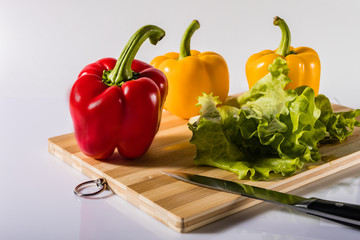 Red and yellow peppers on lettuce on a white background.