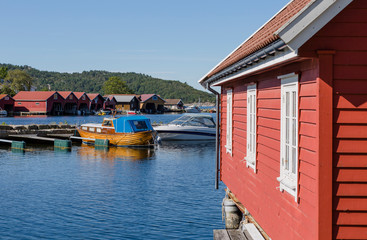 Fototapeta na wymiar Boote und bunte Bootshäuser in Svennevik, Svennevikbukta, Südnorwegen
