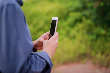 Crop shot view of Asian man's hands holding smart phone with blank copy space ,green background