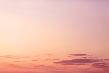 Fototapeta premium Airplane taking off and rising high in pink sunset sky