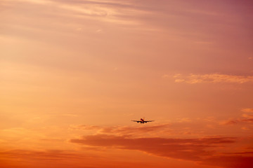 Airplane taking off and flying high in sunset sky