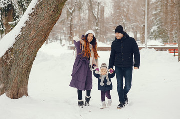 Fototapeta na wymiar Family have fun in a winter park. Stylish mother in a purple jacket. Little girl in a winter clothes. Father with cute daughter