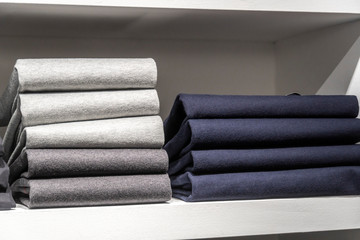 Stack of folded wool sweaters on shelf in a clothing store