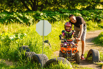 Father and daughter playing on the road at the day time. They driving on quad bike in the park. People having fun on the nature. Concept of friendly family. © Angelov