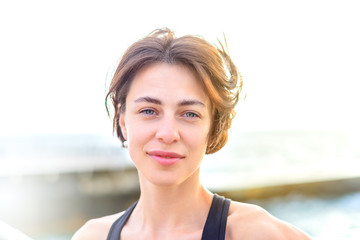 Attractive athletic beautiful girl with middle brown smiling on the backgroung of the sea