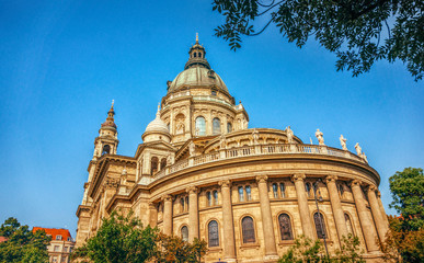 Fototapeta na wymiar Budapest, Hungary - July 14, 2019: majestic facade of the old St. Stephen's Basilica in Budapest and crowd of tourists on the street, Hungary. Great Catholic Cathedral, built in the Baroque style. Bud