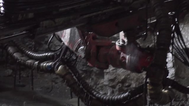 Reveal of underground machinery drilling into rock with water spurting out