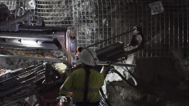Person working underground loading rods into jumbo for mesh bolting