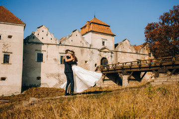 Obraz premium The groom twists his bride in his arms against the backdrop of the castle