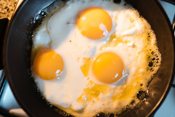 Egg omelette is being prepaired in a frying pan close up - Three yellow eggs in Eastern Europe Latvia Riga