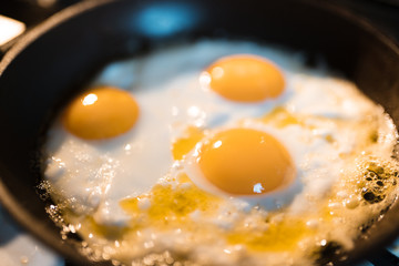 Egg omelette is being prepaired in a frying pan close up - Three yellow eggs in Eastern Europe Latvia Riga