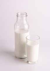 Fresh milk. Glass bottle of milk and a glass close-up. Still life bottle of milk and a glass on a white background.