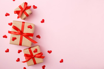 Presents with red bow on pink background with heart confetti. Flat lay style. Valentine day concept