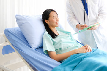 Obraz premium Close up Asian Male doctor is talking to female patients lie in bed in the hospital room about the diagnosis of her illness.disease treatment and health care concept