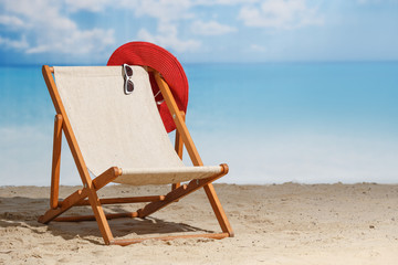 Beach deck chair on a sandy beach by the sea. Summer mood. Space to copy - obrazy, fototapety, plakaty